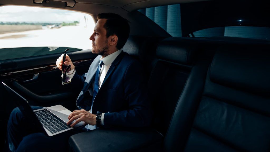 business man travelling in a taxi with laptop